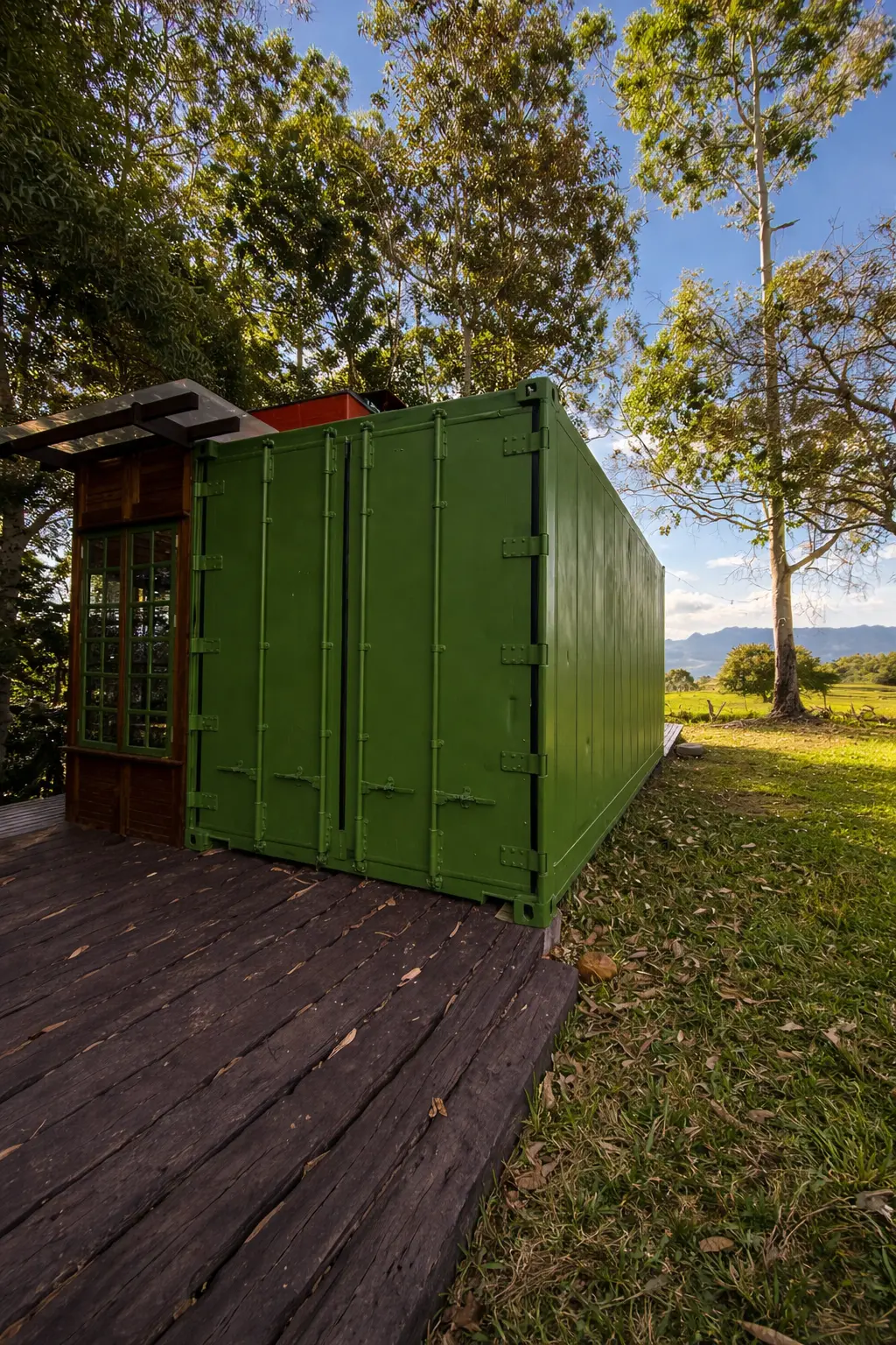 Cabana container verde vista de dia, em meio às árvores e ao gramado