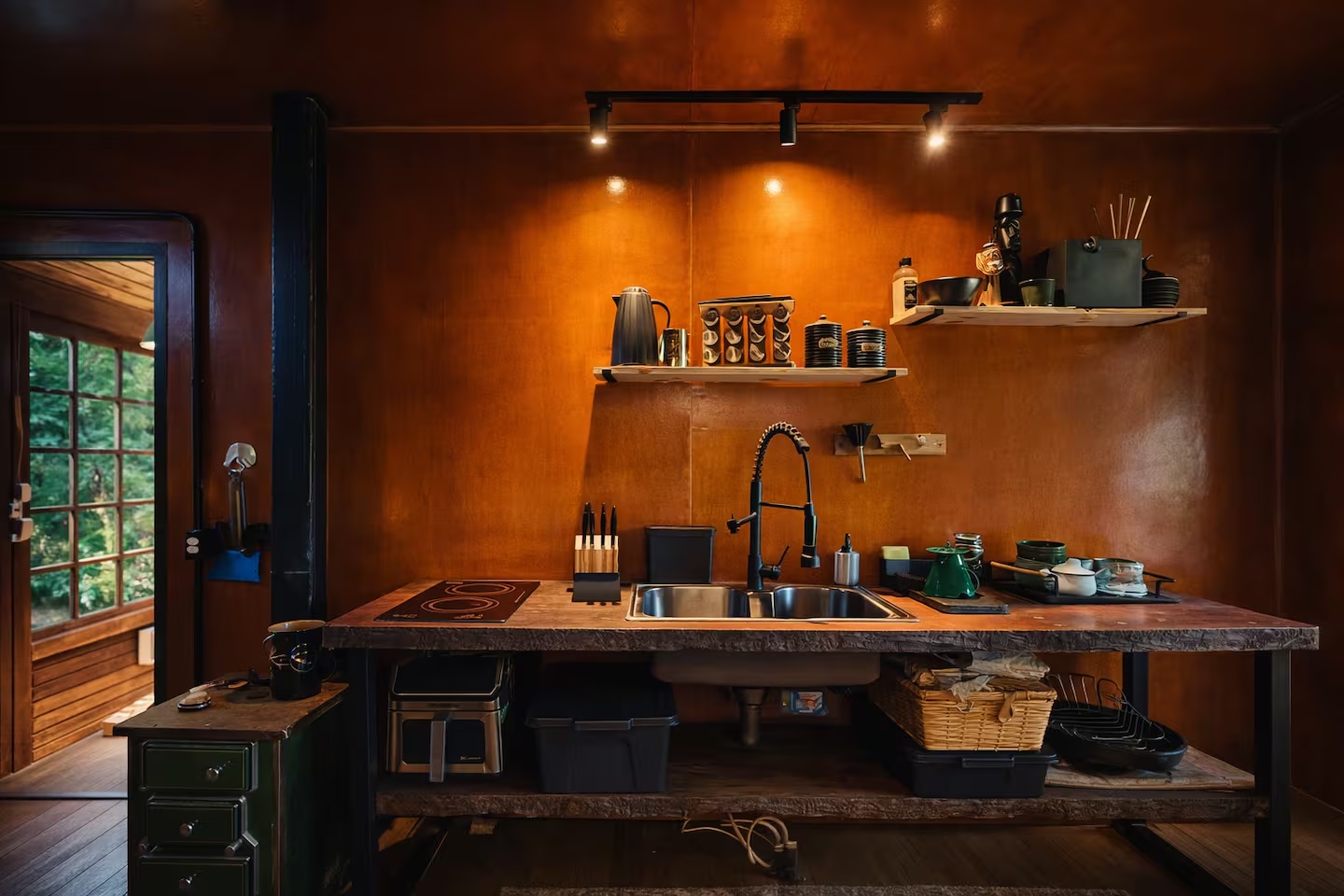 Cozinha ampla da cabana com bancada de madeira e vista para o gramado