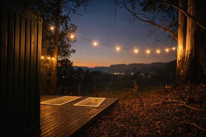 Luzes no deck e vista para o vale ao anoitecer na propriedade