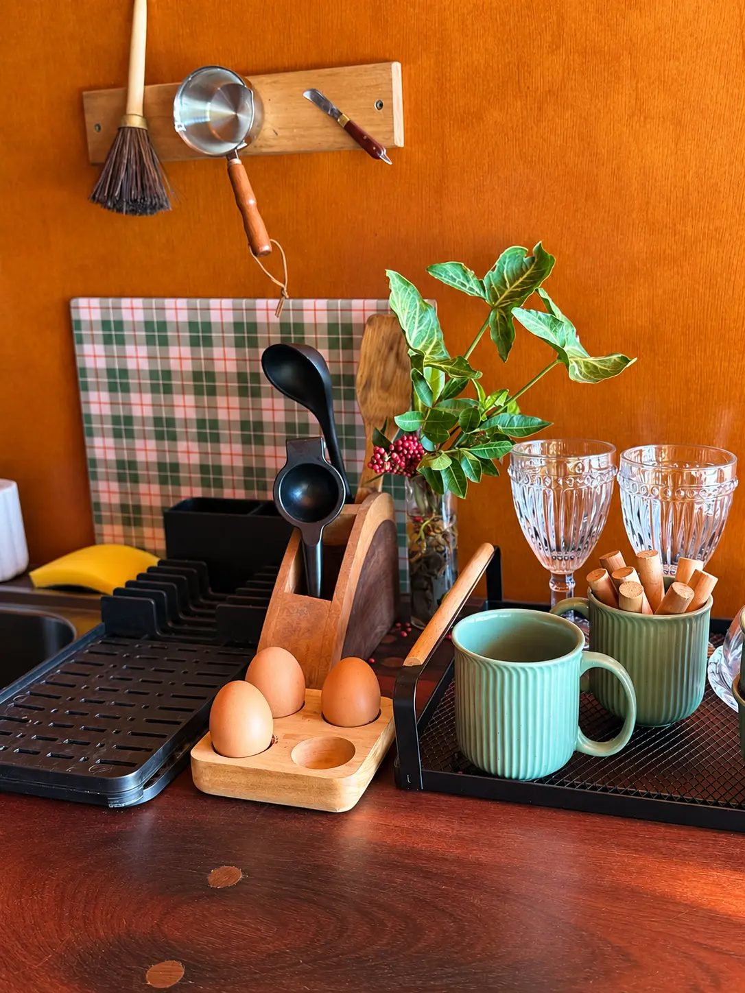 Detalhes da cozinha: canecas verdes, taças e utensílios sobre a bancada