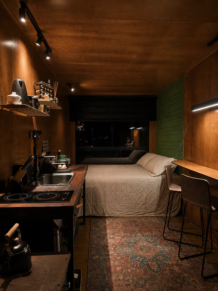 Interior aconchegante da cabana com cama de casal e bancada de madeira
