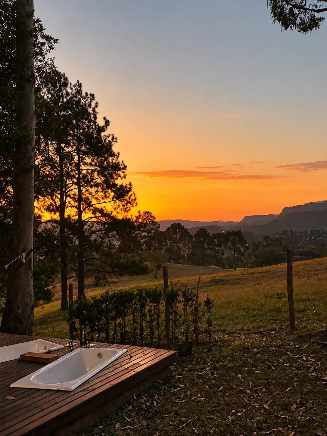 Banheiras ao ar livre no deck durante o pôr do sol, entre as árvores